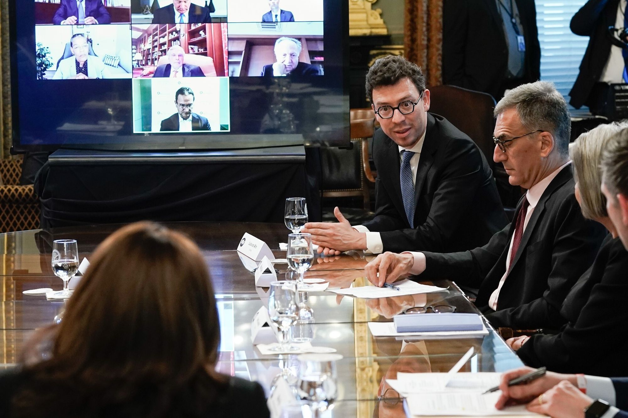 Una foto del CEO de Duolingo, Luis von Ahn, sentado a una mesa grande. En frente está la vicepresidenta Kamala Harris, con su espalda hacia el fotógrafo. Luis está hablando directamente a la vicepresidenta