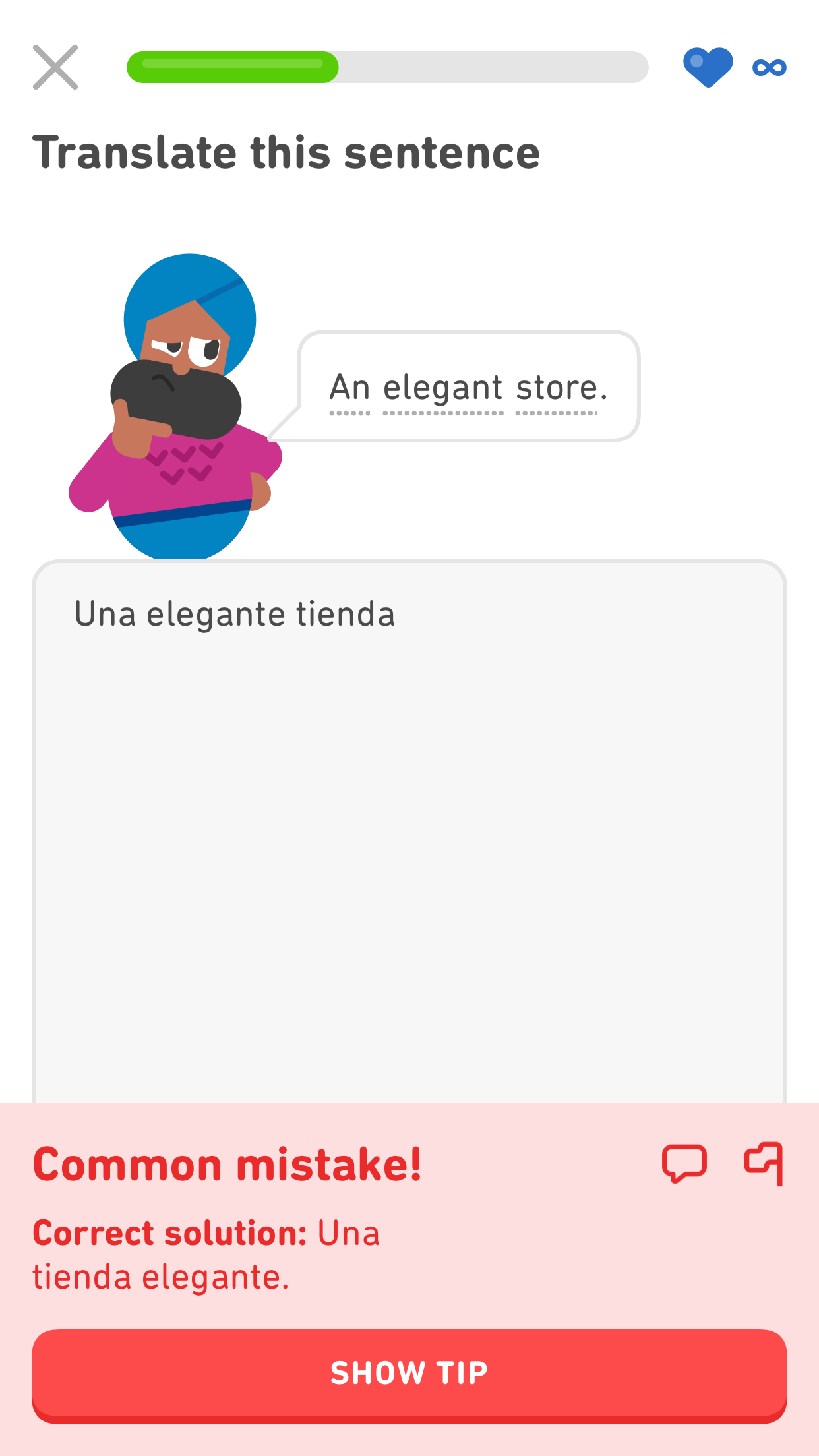 Captura de pantalla de un ejercicio de Duolingo eb inglés donde el personaje Vikram dice “una tienda elegante” en inglés. La traducción ingresada es “una elegante tienda”. El mensaje de corrección en la parte inferior dice “¡Es un error común!” y muestra la solución correcta con el sustantivo y el adjetivo invertidos: “Una tienda elegante”.