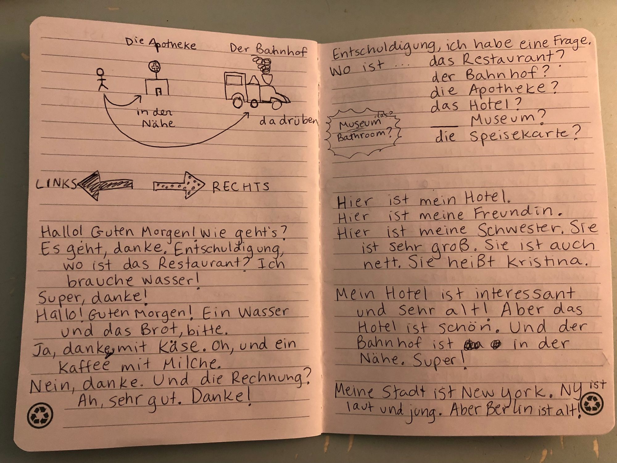 Photograph of two more pages of an open notebook. They show some drawings with labels in German, some paragraphs and mini dialogues in German, and lists of words and questions in German.