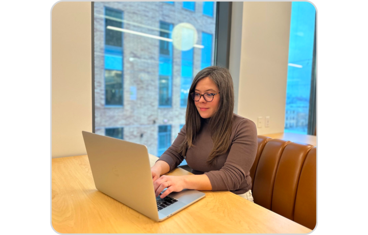 Sophie Wodzak, author of this post and hardworking Duo, sits at her laptop computer in a stylish brown turtleneck working on her next great blog post