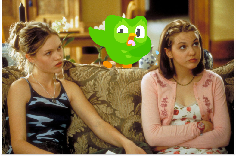 Still shot from the movie "10 Things I Hate About You", of Kat and Bianca sitting angrily on the couch and a photoshopped Duolingo owl standing between them looking disgusted