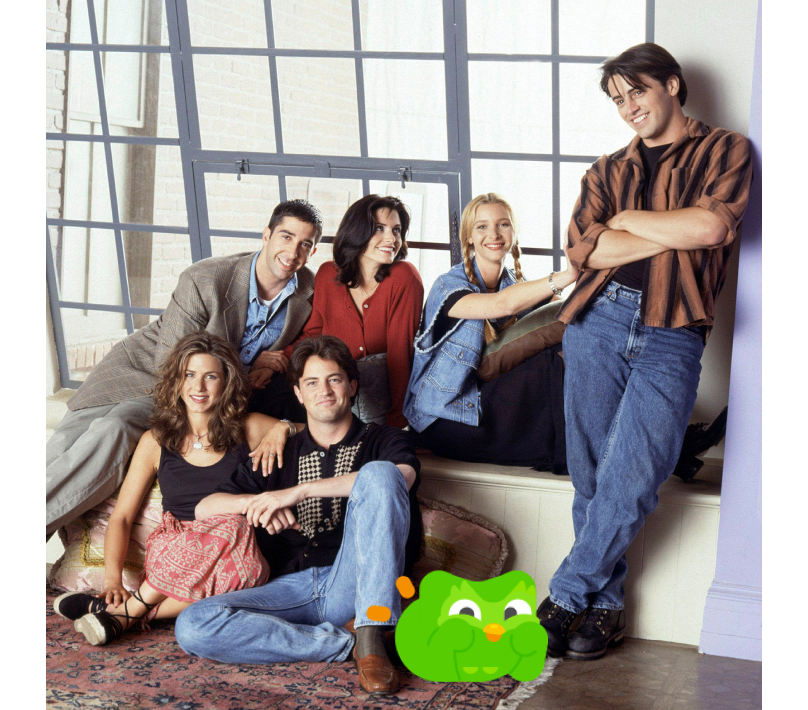 Still shot of the cast from "Friends" with the Duolingo owl photoshopped on the floor with them