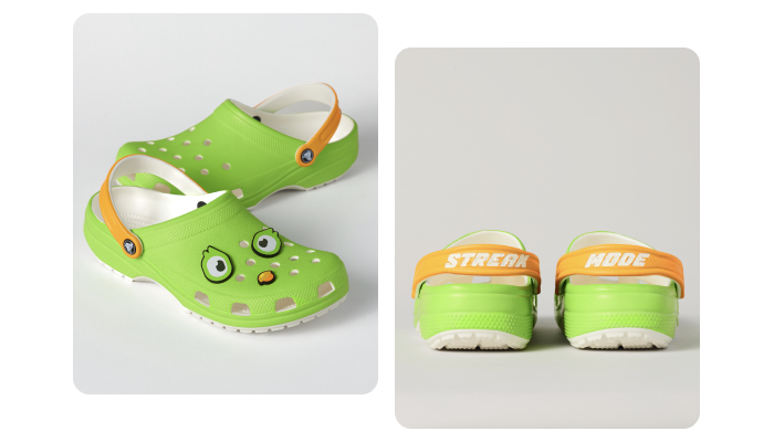 Lime green crocs with orange straps that read "STREAK" on the left shoe and "MODE" on the right, so that when lined up the shoes read STREAK MODE from the back. On the front of the crock, three Jibbitz are arranged to look like Duo's face: there are two eye-shaped Jibbitz and one that is Duo's orange beak