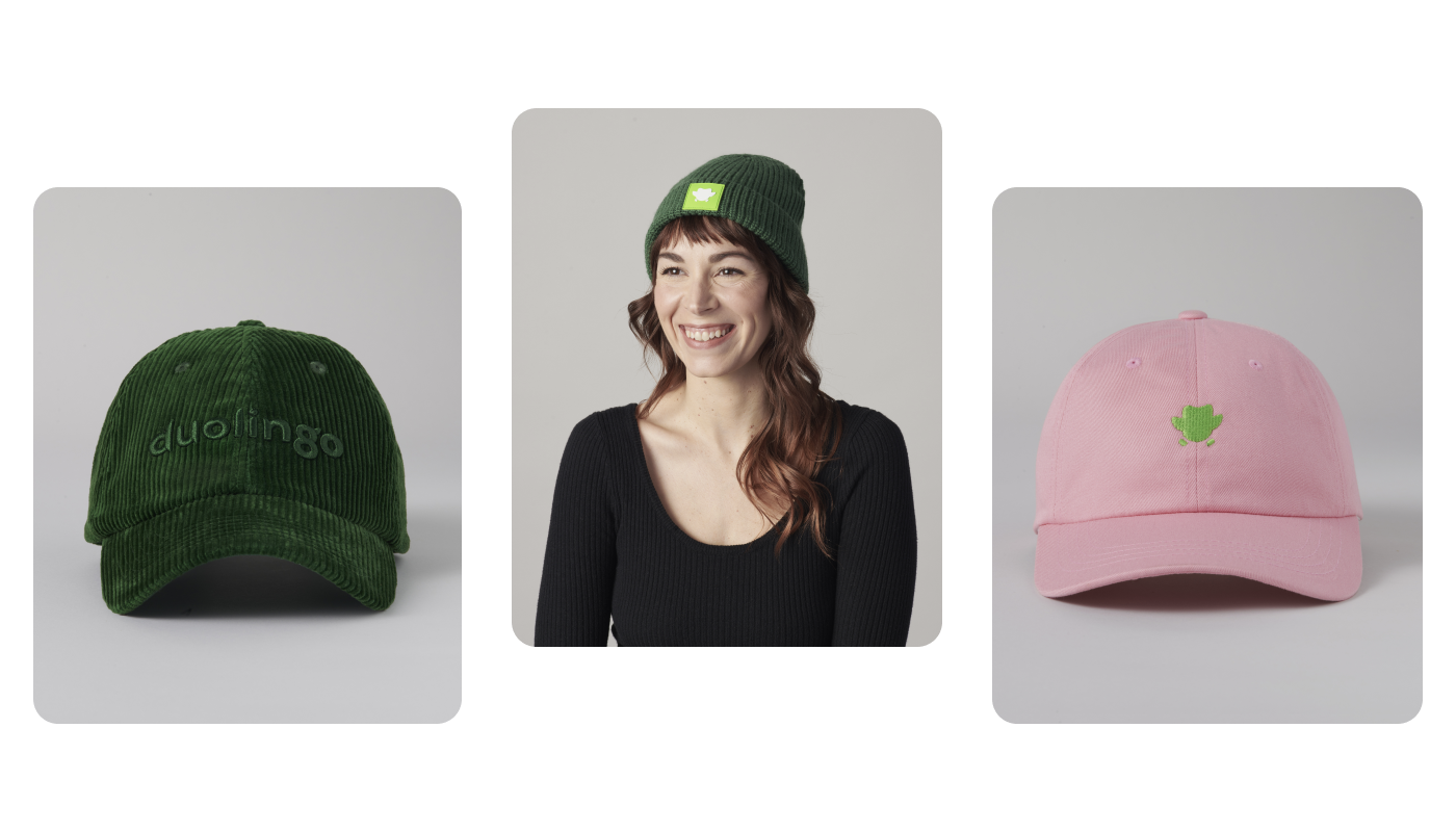 Three photographs of Duolingo hats. The first is a dark green corduroy hat with “duolingo” sewn on the front. The second is a brunette woman wearing a dark green beanie with a lime green Duo the owl silhouette on the edge of the beanie. The last is a pink canvas baseball cap with a small green Duo silhouette sewn on the front.