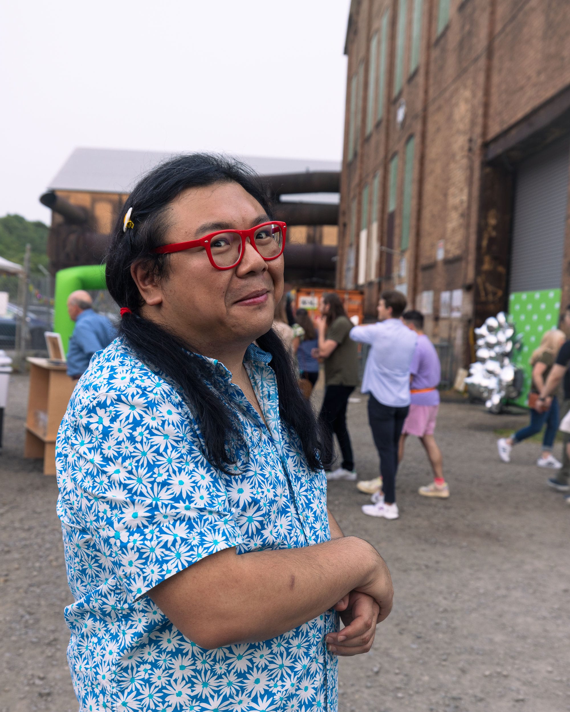 Photo de Duo qui sourit debout devant un immeuble et une foule de personnes