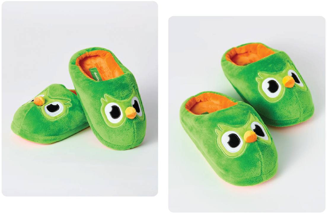 Green plush slippers featuring Duo the owl. The slippers have an interior orange lining and embroidered owl face on the top of the slipper with Duo’s beak protruding from the top of the slipper.