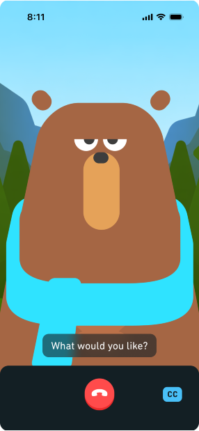 Screenshot des Videocalls mit Falstaff. Falstaff, der Bär, sieht den Lesenden mit einem ernsten Gesichtsausdruck an. Die Bildunterschrift darunter zeigt eine Frage auf Englisch: „What would you like?“ Am unteren Bildschirmrand befindet sich ein rotes Telefonsymbol zum Beenden des Anrufs. Rechts befindet sich ein blaues Rechteck mit den Buchstaben „CC“, das die Möglichkeit bietet, Untertitel ein- oder auszublenden.