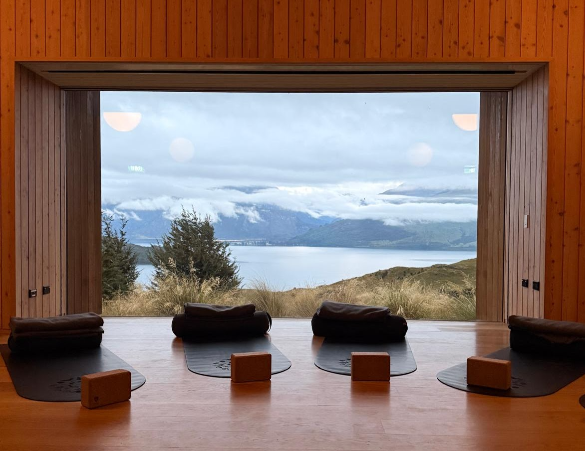 One of Aro Ha’s wellness rooms, with yoga blocks, mats, and towels in the foreground and a window overlooking mountains and water.